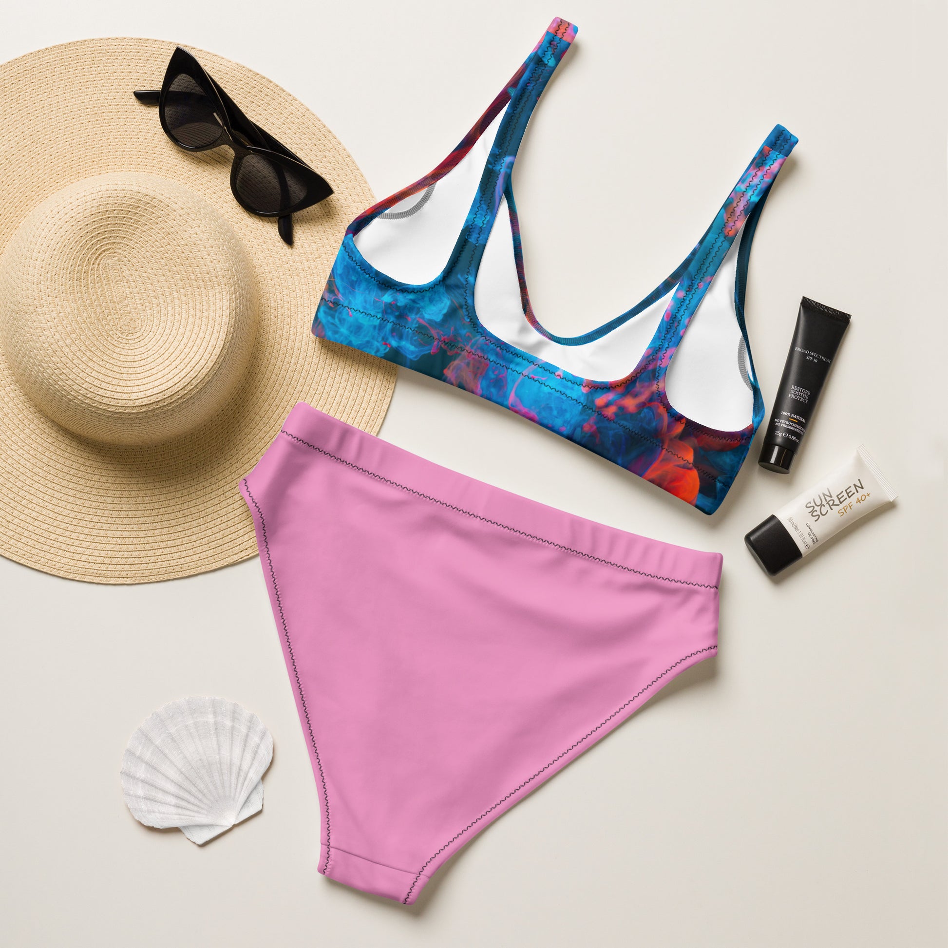 Female model wearing a red‑blue patterned bikini top with high‑waisted pink bottoms, AMMOR PARIS recycled bikini set showcased in a refined studio environment to highlight the brand’s Paris‑born luxury identity, modern designer swimwear aesthetic and elevated sustainable fashion direction.